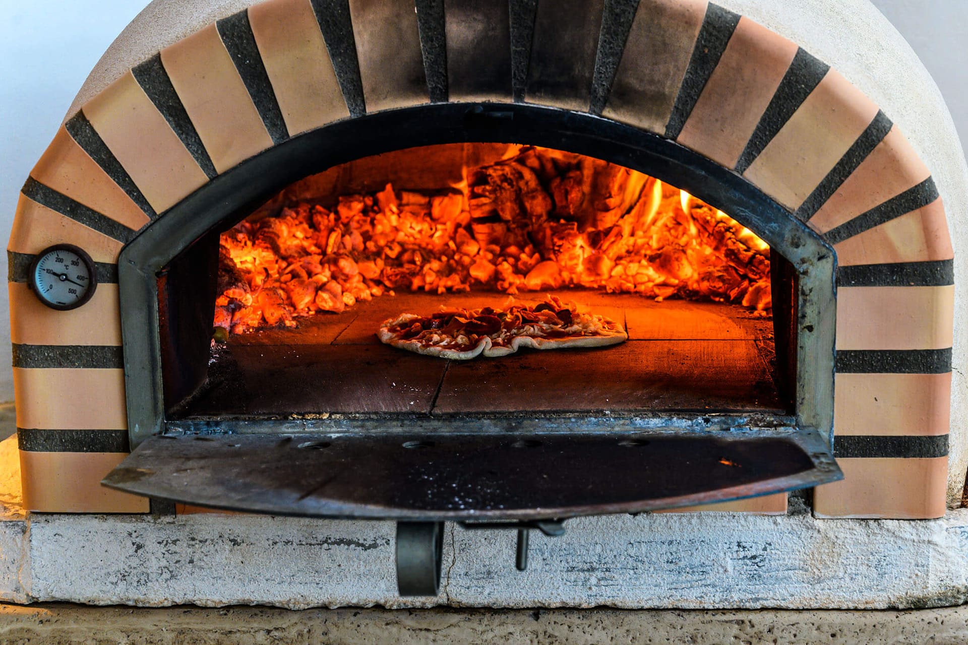 A pizza baking in the wood-fired oven.